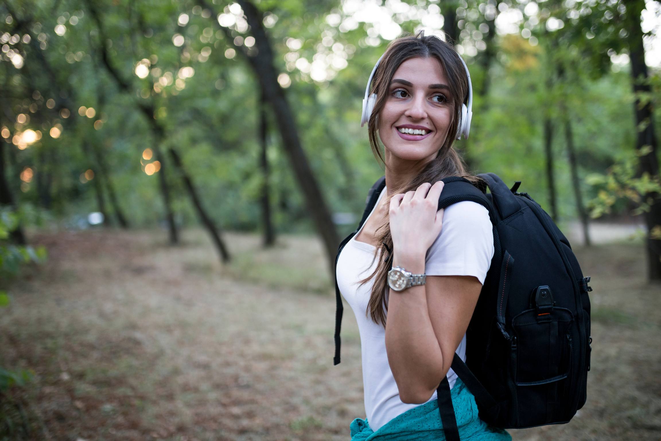 A girl smiling with headphones on in the forest
