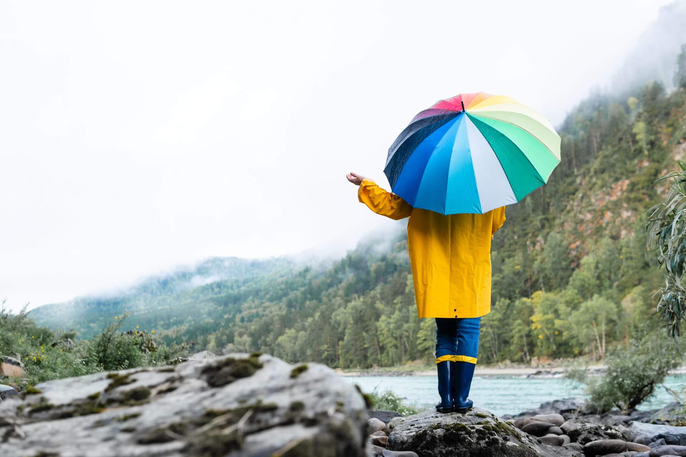 girl in yellow jacket holding colourful umbrella