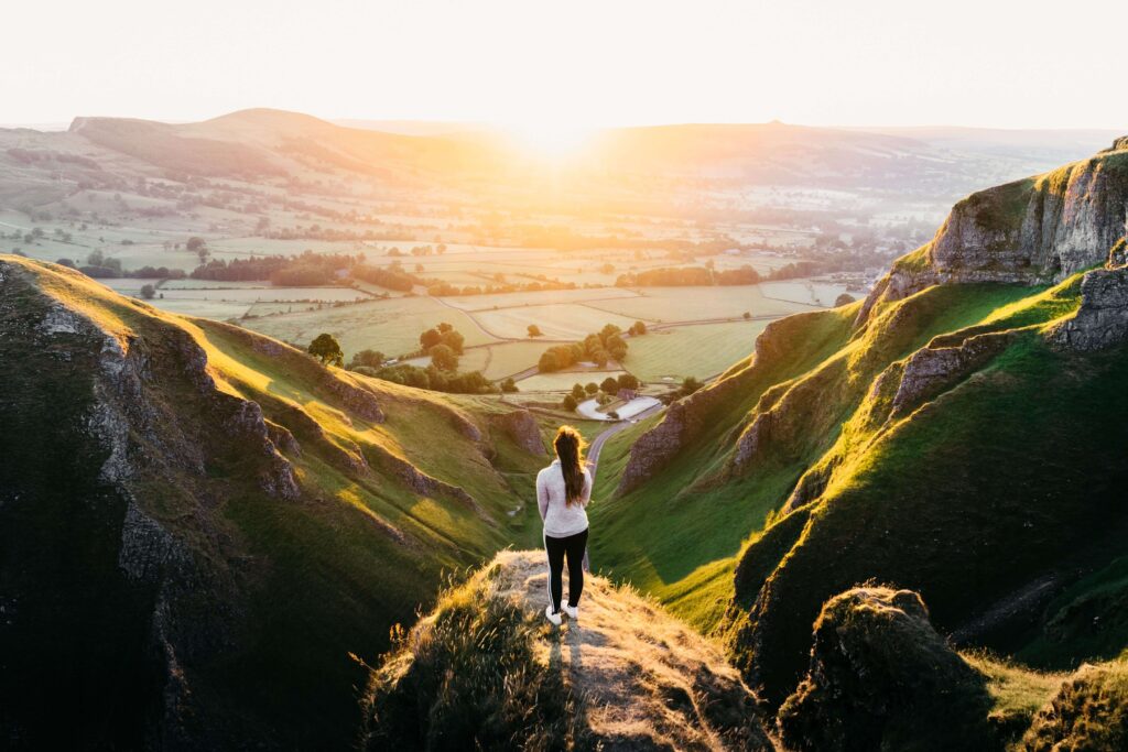 Girl standing on a rock at sunset at Winnats Pass, Peak District