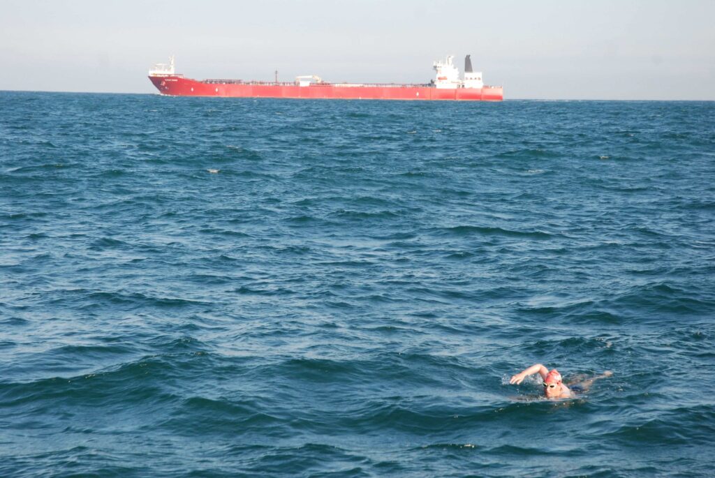 Woman swimming the channel with a shipping tanked in the background