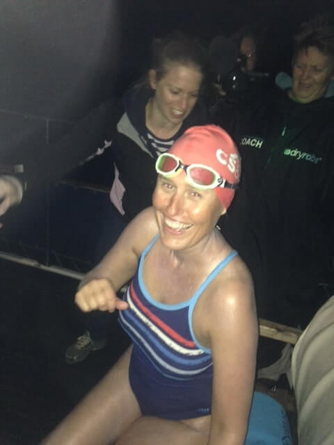 Woman smiling in her swimming costume sat in a boat in the dark 