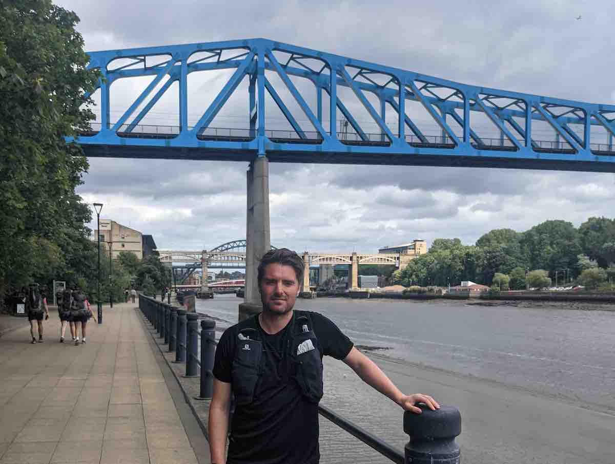 Man standing in front of the Tyne River Bridge in Newcastle