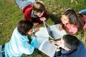 group of teenagers studying on grass