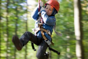 A young boy zip lining in a forest