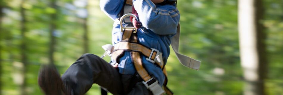 A young boy zip lining in a forest